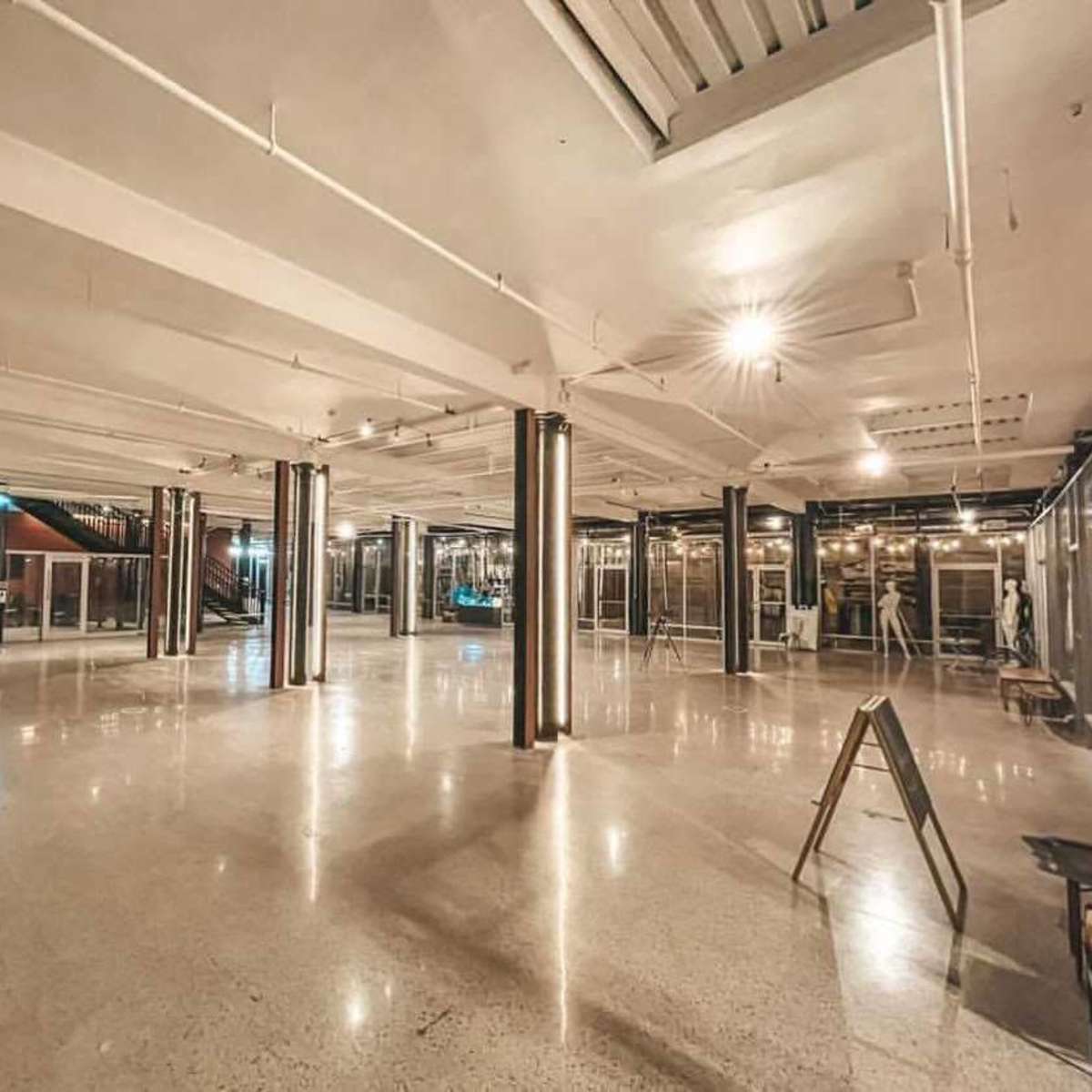 A spacious, empty indoor area with polished concrete floors and metallic columns supporting the ceiling.