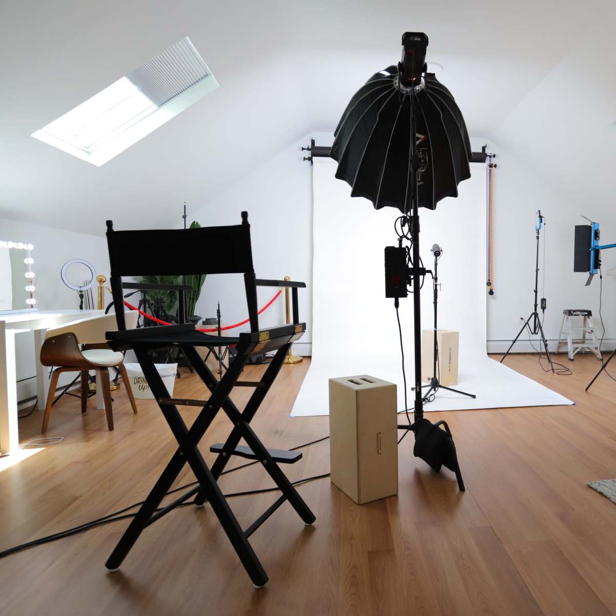 A photography studio is set up with lighting equipment, a backdrop, and a director's chair.