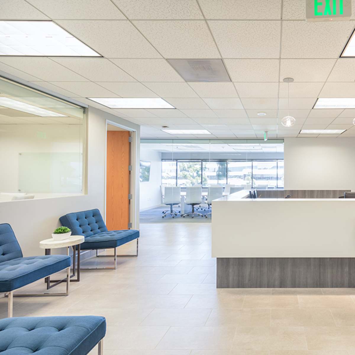 A modern office reception area with blue seating, a reception desk, and a spacious workspace visible in the background.