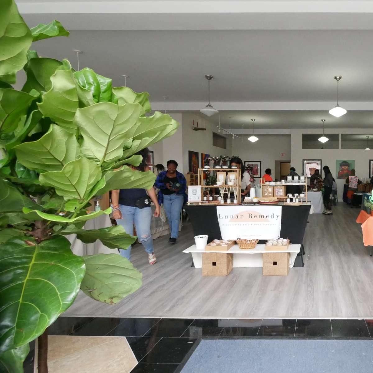 A busy indoor market filled with tables displaying plants and various products, while people browse and shop.