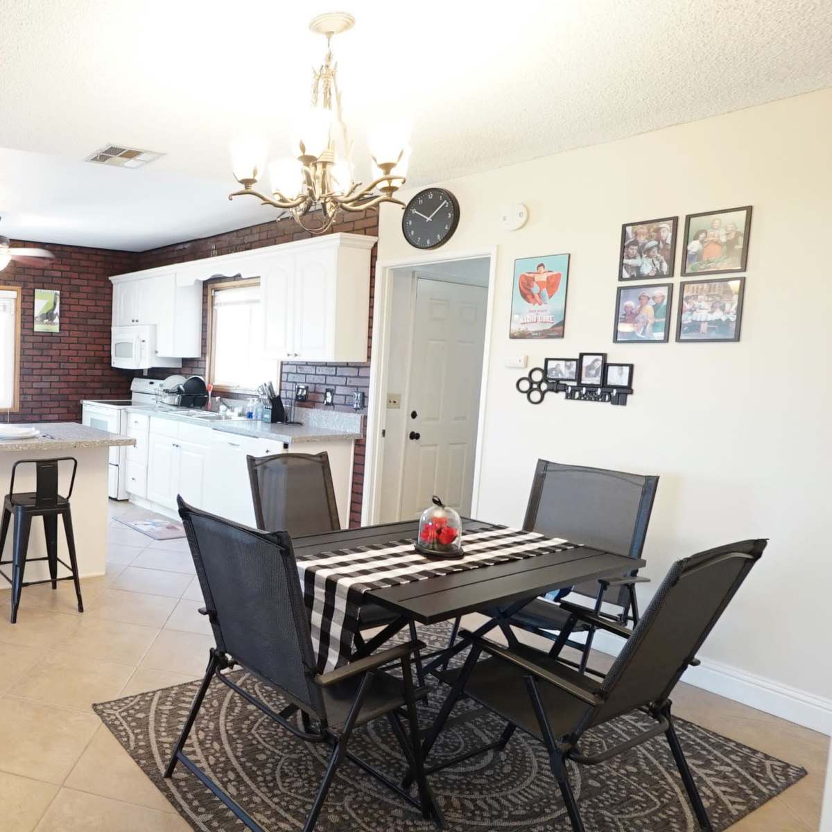 A kitchen and dining area featuring white cabinets, a central island with bar stools, and a dining table set for multiple people.