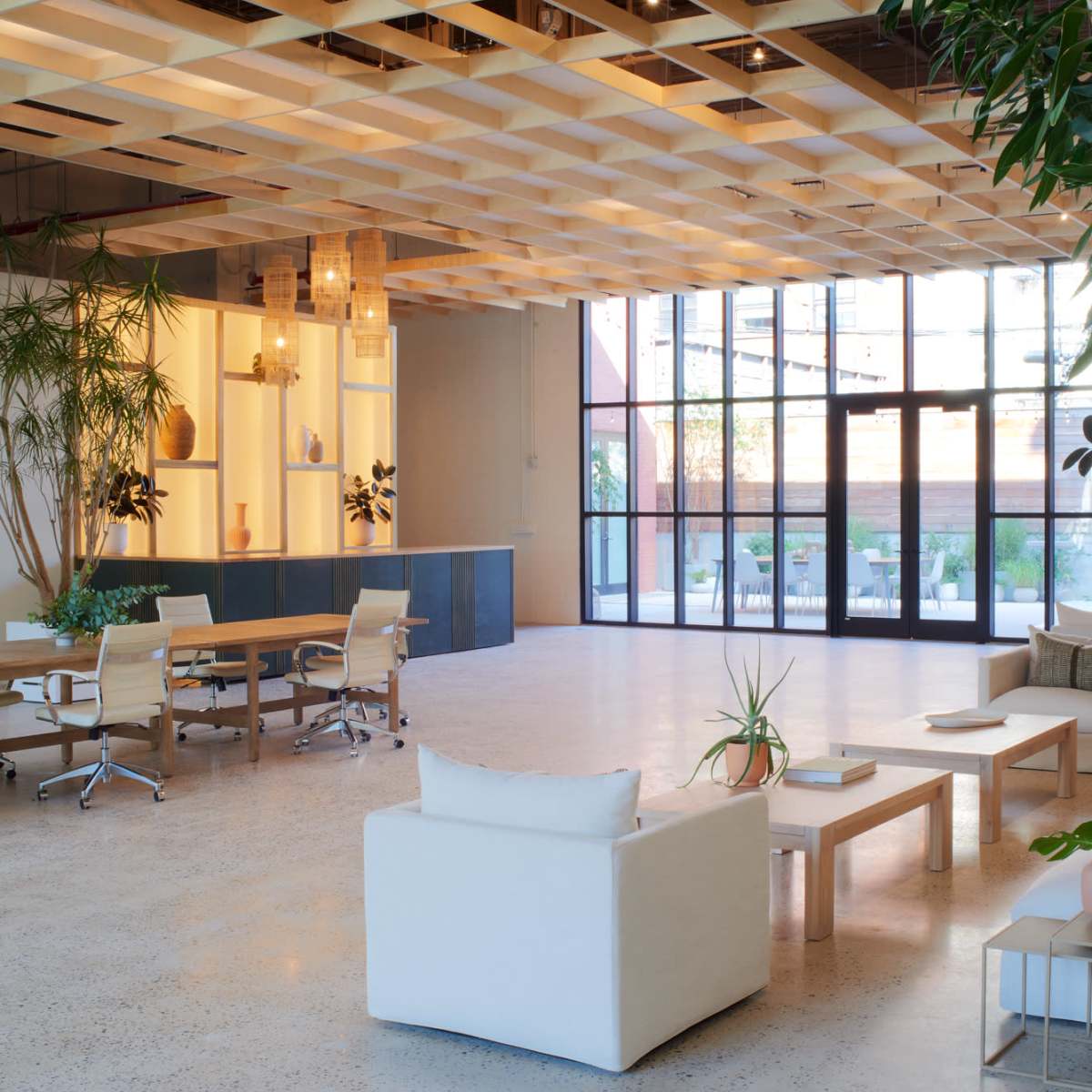 A spacious and modern interior with a seating area, a wooden dining table, and large windows that provide natural light.