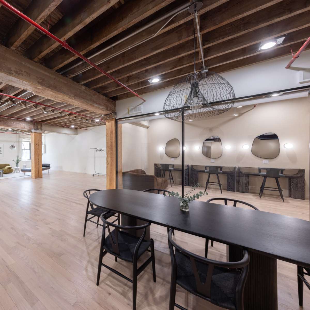 A spacious, modern interior featuring wooden beams, a dining table, and a seating area with plush furniture.
