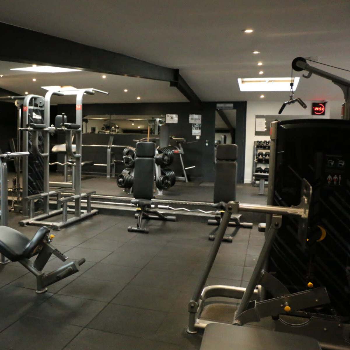 A well-equipped gym featuring various weightlifting machines, benches, and free weights arranged in an open space.