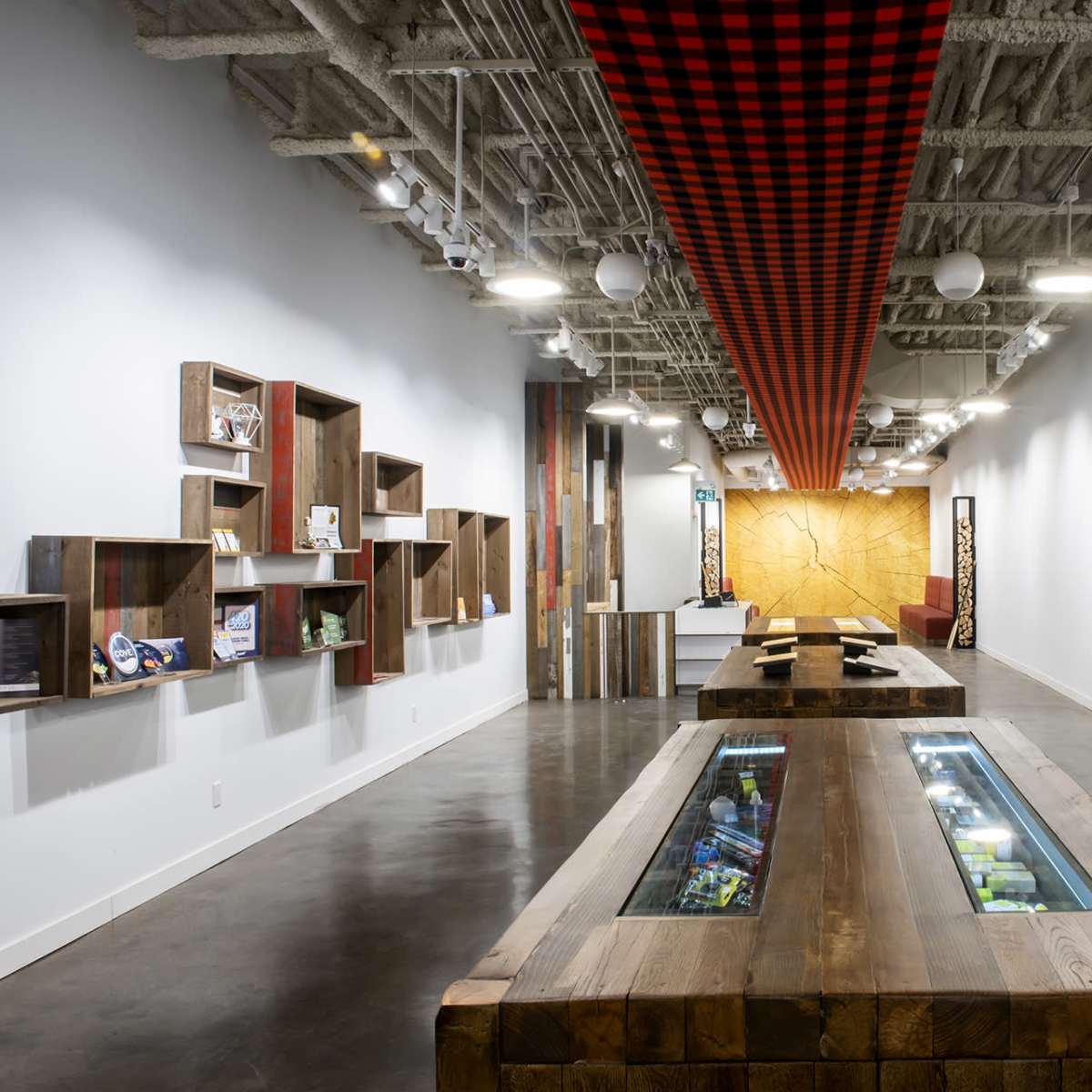 A modern retail space with wooden display tables, a chevron-patterned wood wall, and a checkered ceiling design.