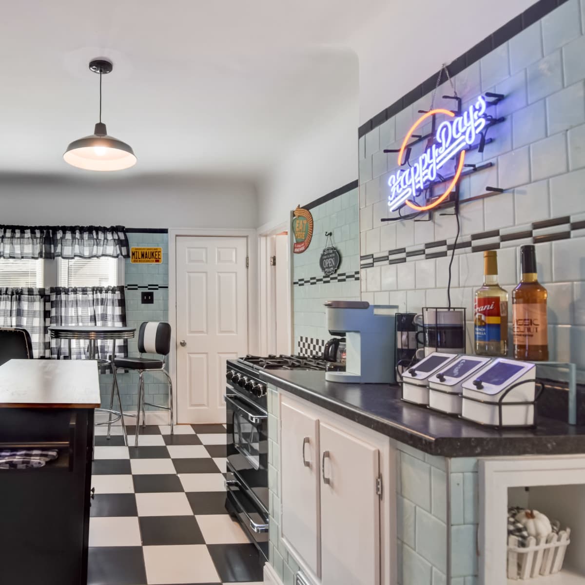 The kitchen features black and white checkered floors, a central island, and modern appliances alongside vintage decor.