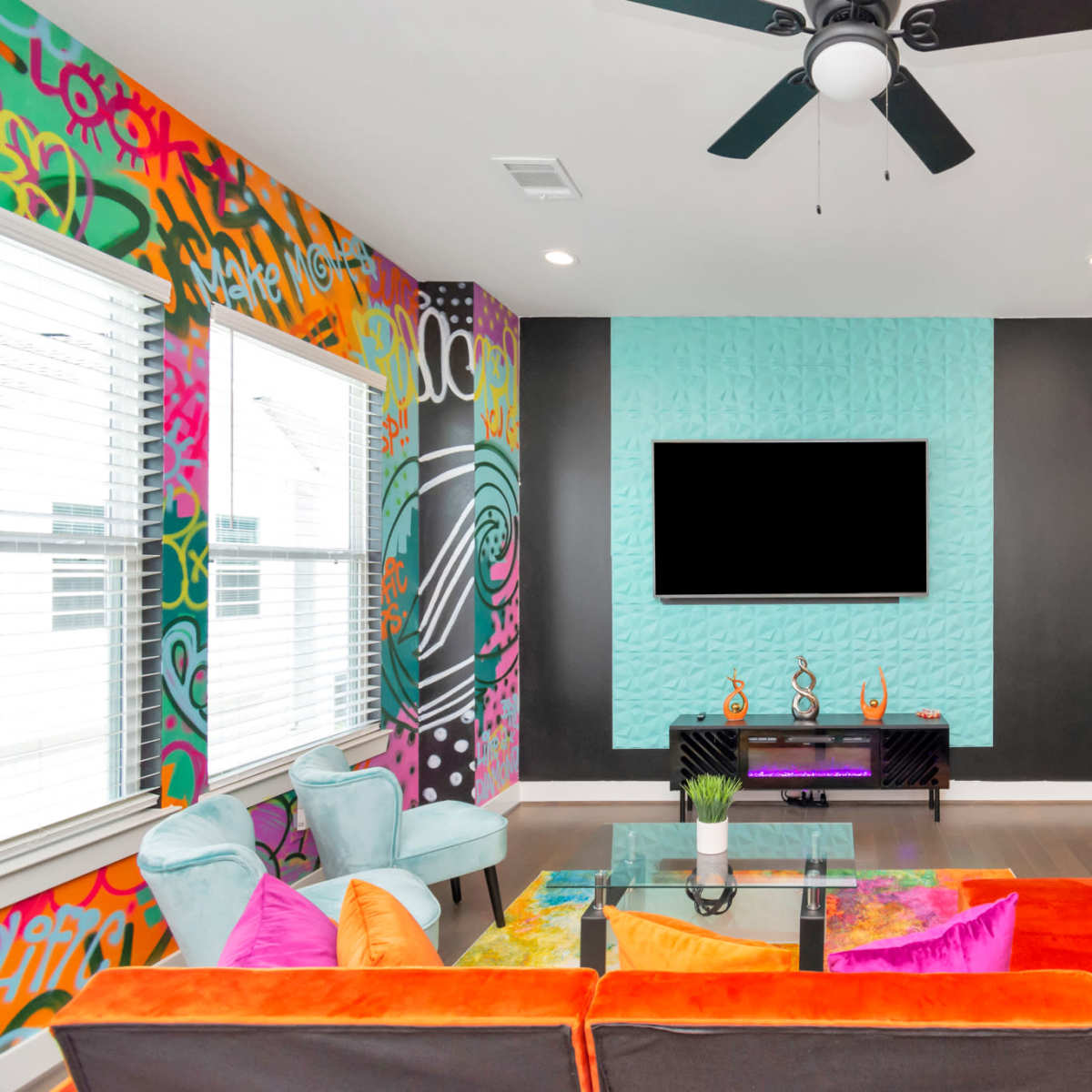 A modern living room with colorful wall art, a large television mounted on the wall, and a sectional sofa in vibrant colors.