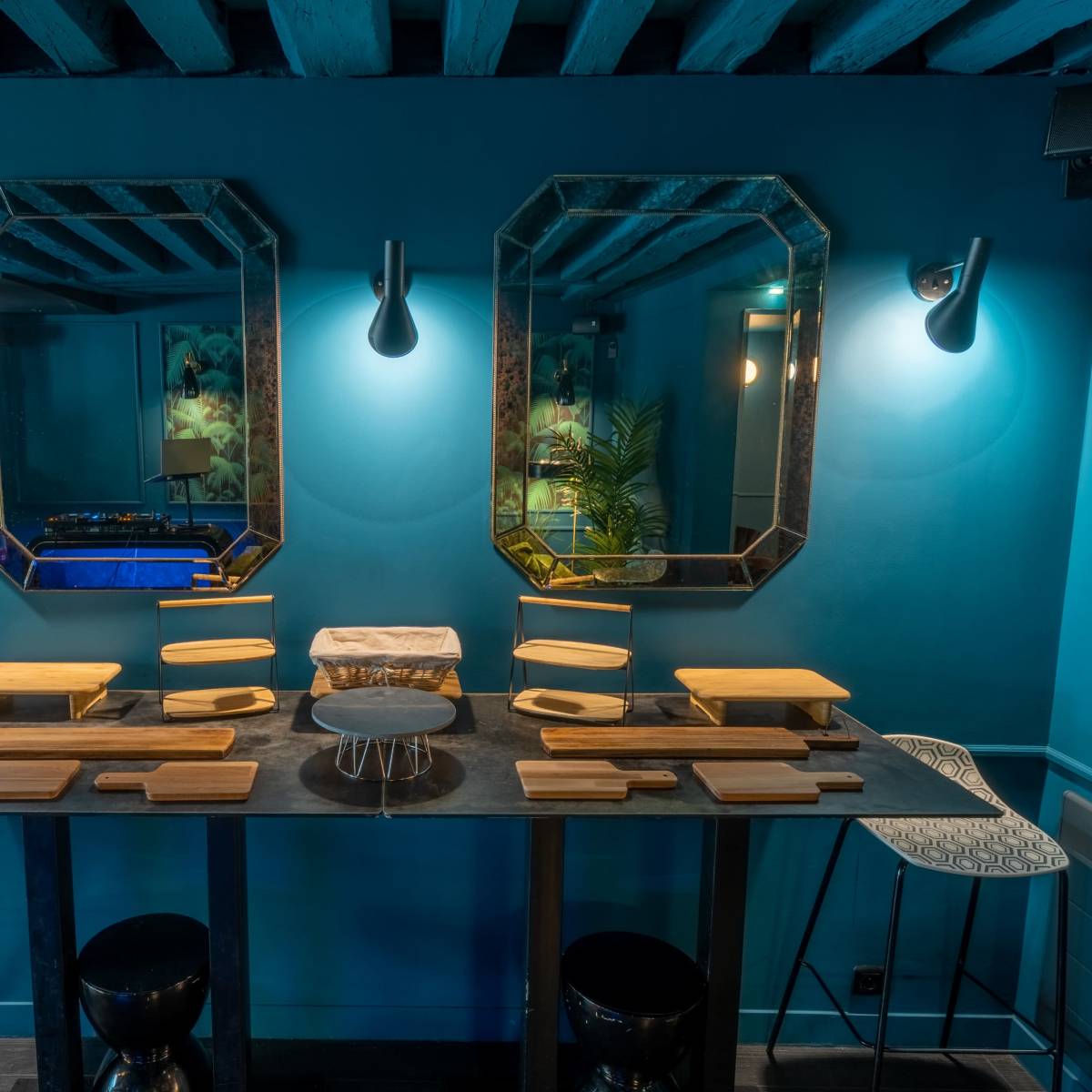A modern dining area with a blue wall, two ornate mirrors, and a long table set with multiple wooden platters.
