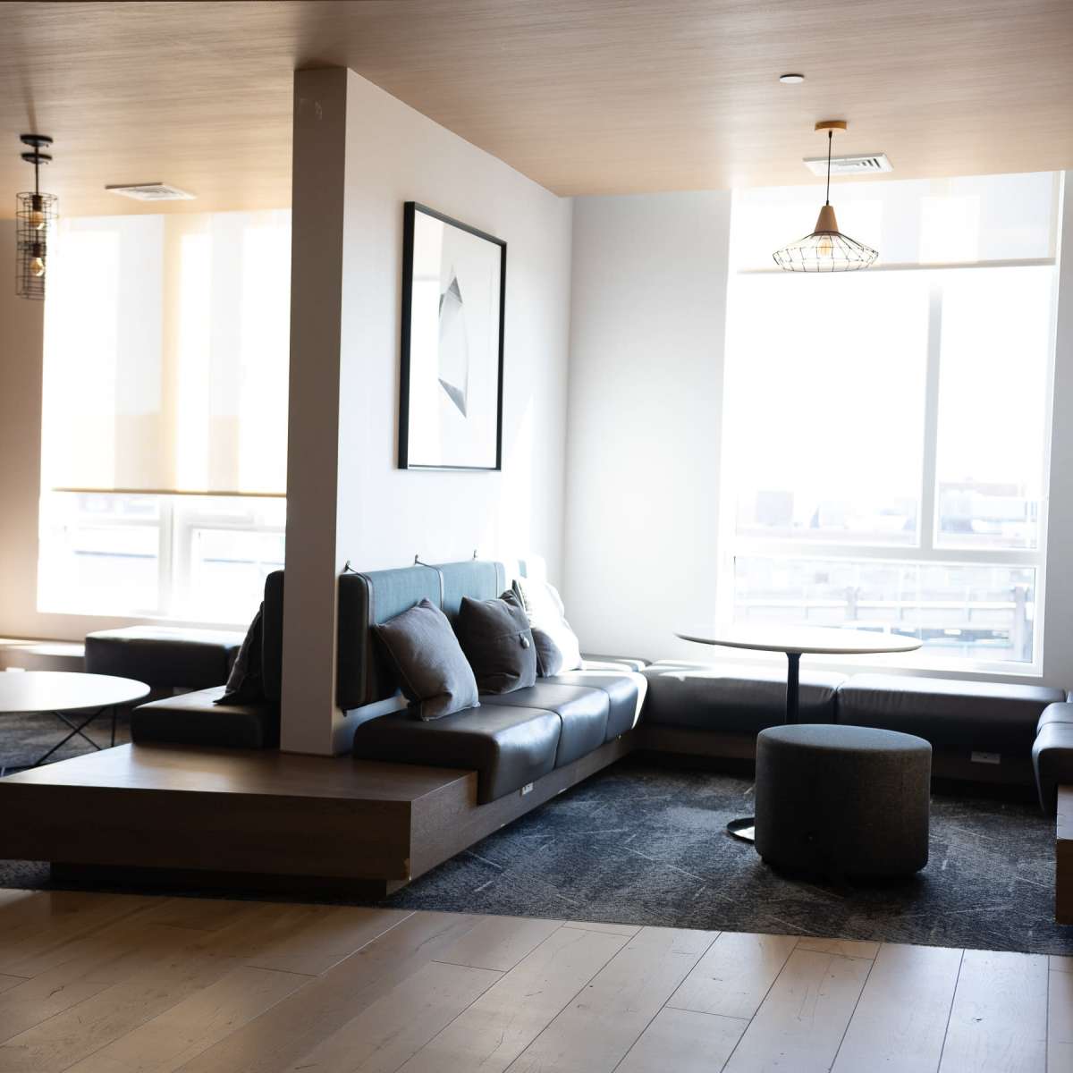 A modern lounge area with a sectional sofa, circular coffee table, and large windows letting in natural light.