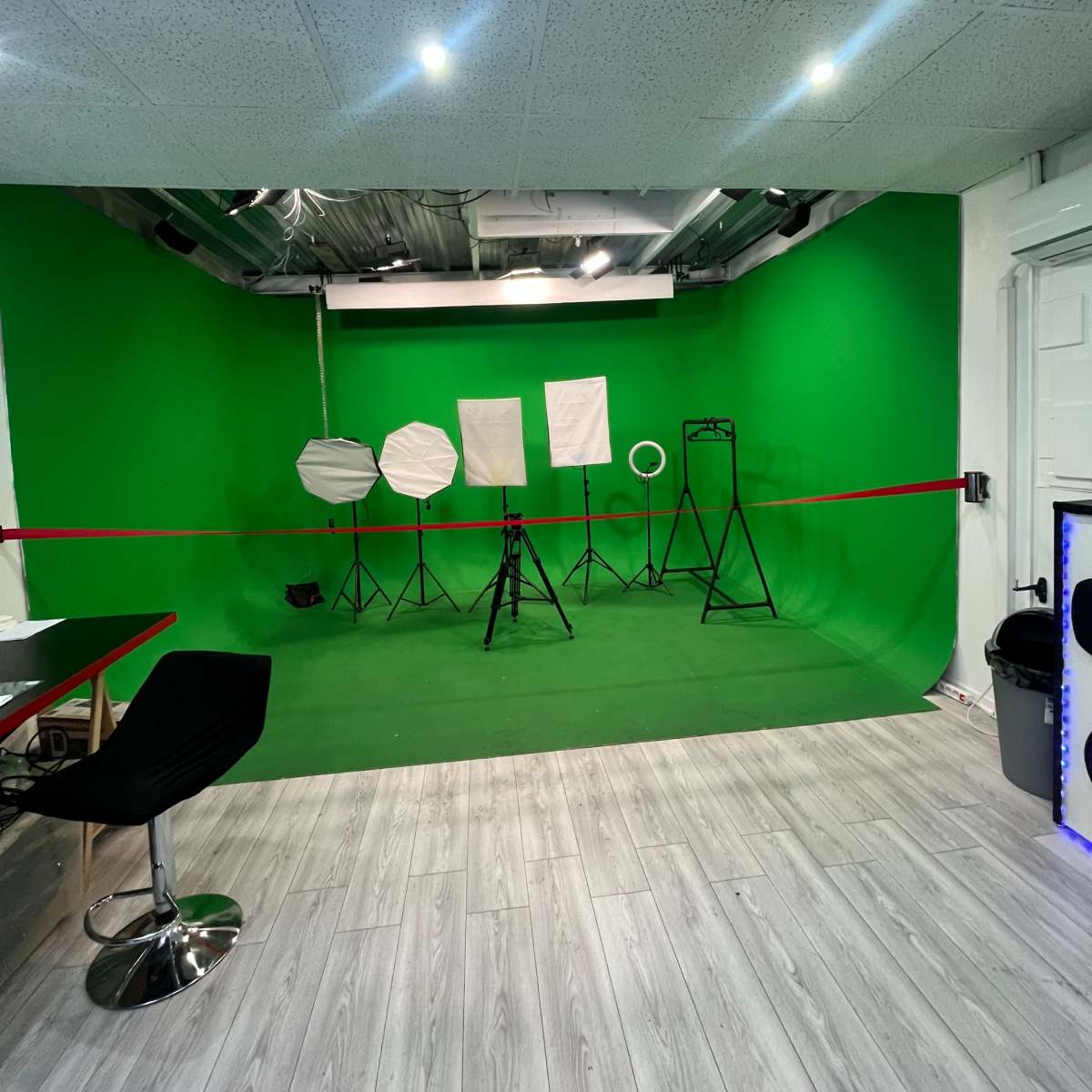 A green screen studio with various lighting equipment arranged in front of a green backdrop.