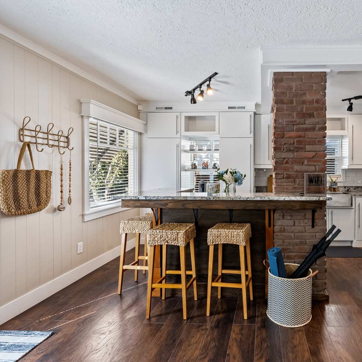 A kitchen featuring a stone column with a breakfast bar, three stools, and light-colored cabinetry.