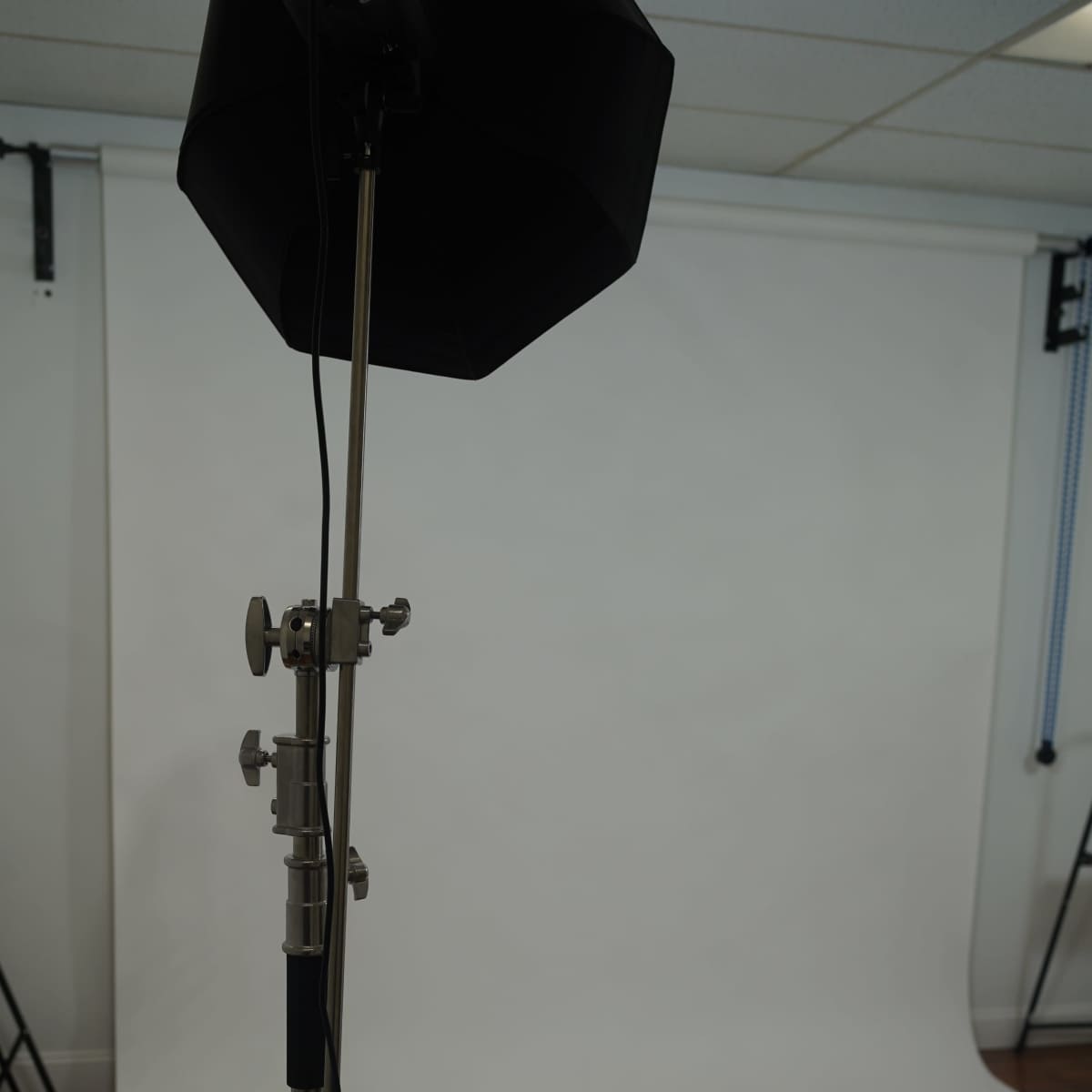 A photography studio setup features a light stand and a backdrop with a smooth, white surface.