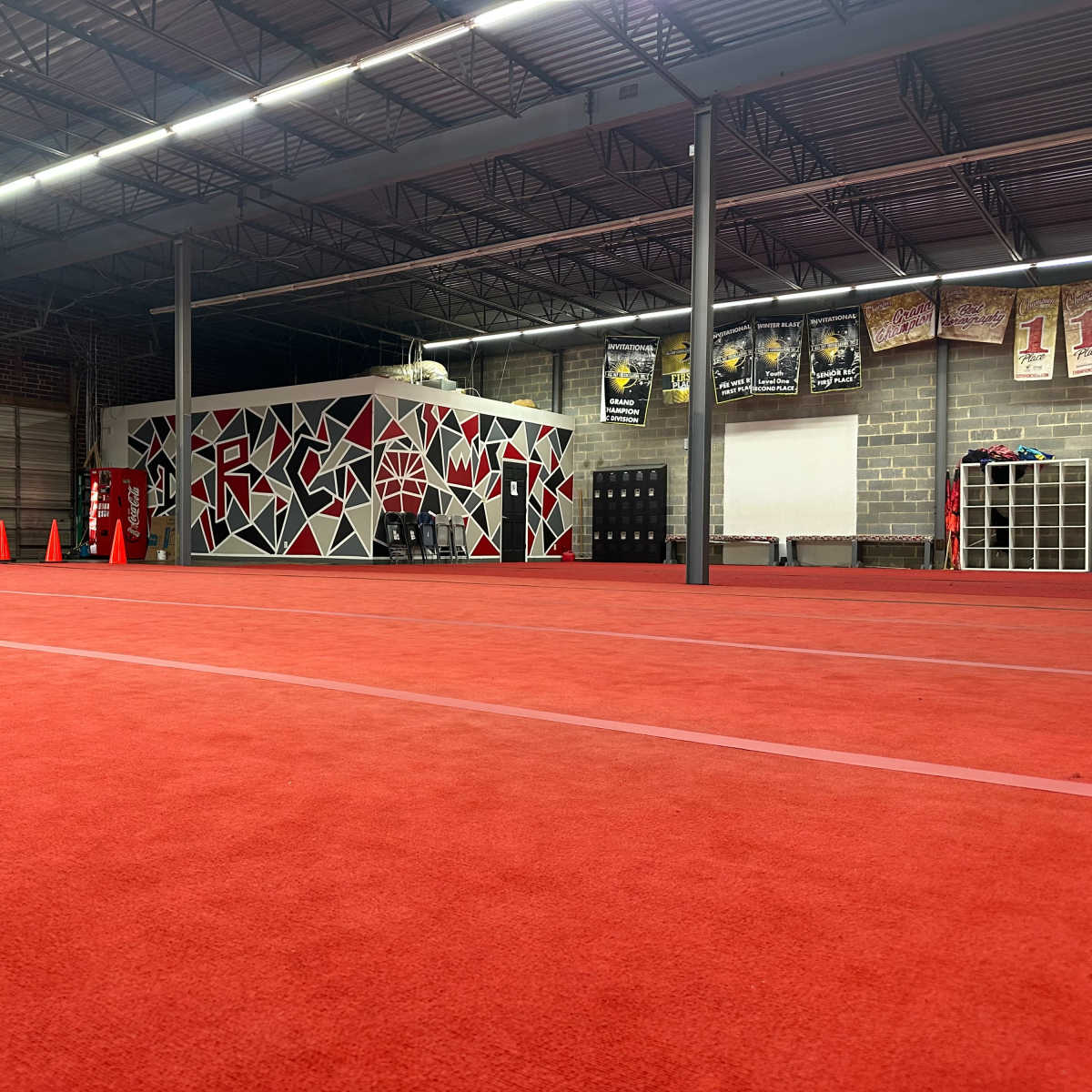 An indoor training facility with a red carpeted floor and a brightly painted wall featuring geometric shapes.