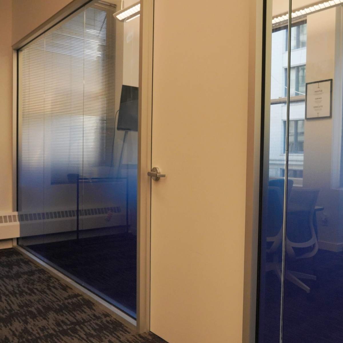 A modern office space with two glass-walled conference rooms separated by a door.