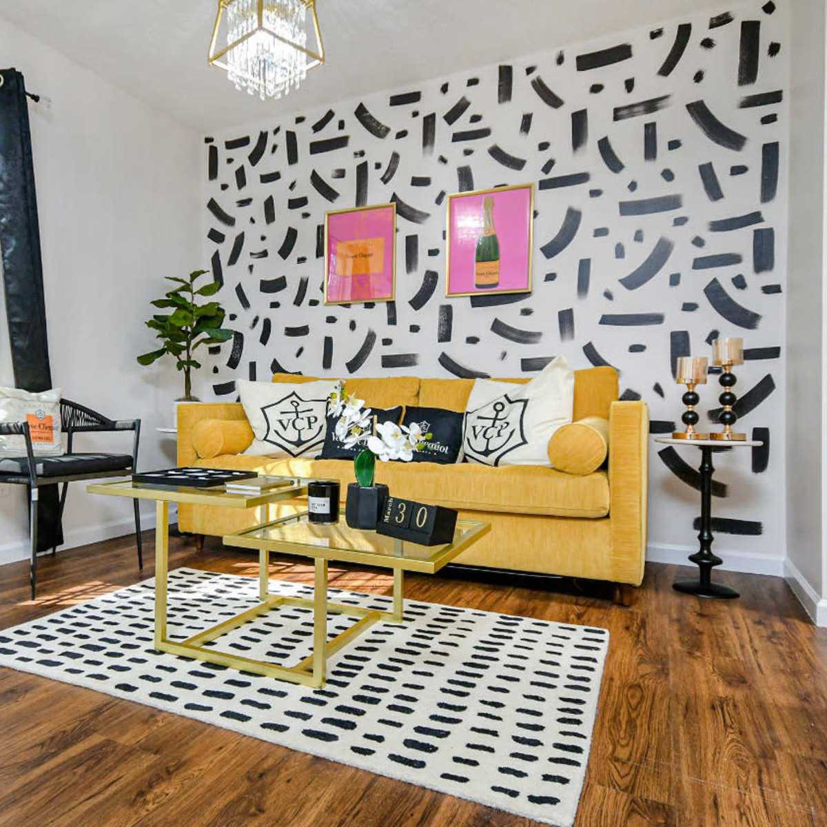 A living room with a yellow sofa, black and white decorative accents, and a coffee table on a patterned rug.
