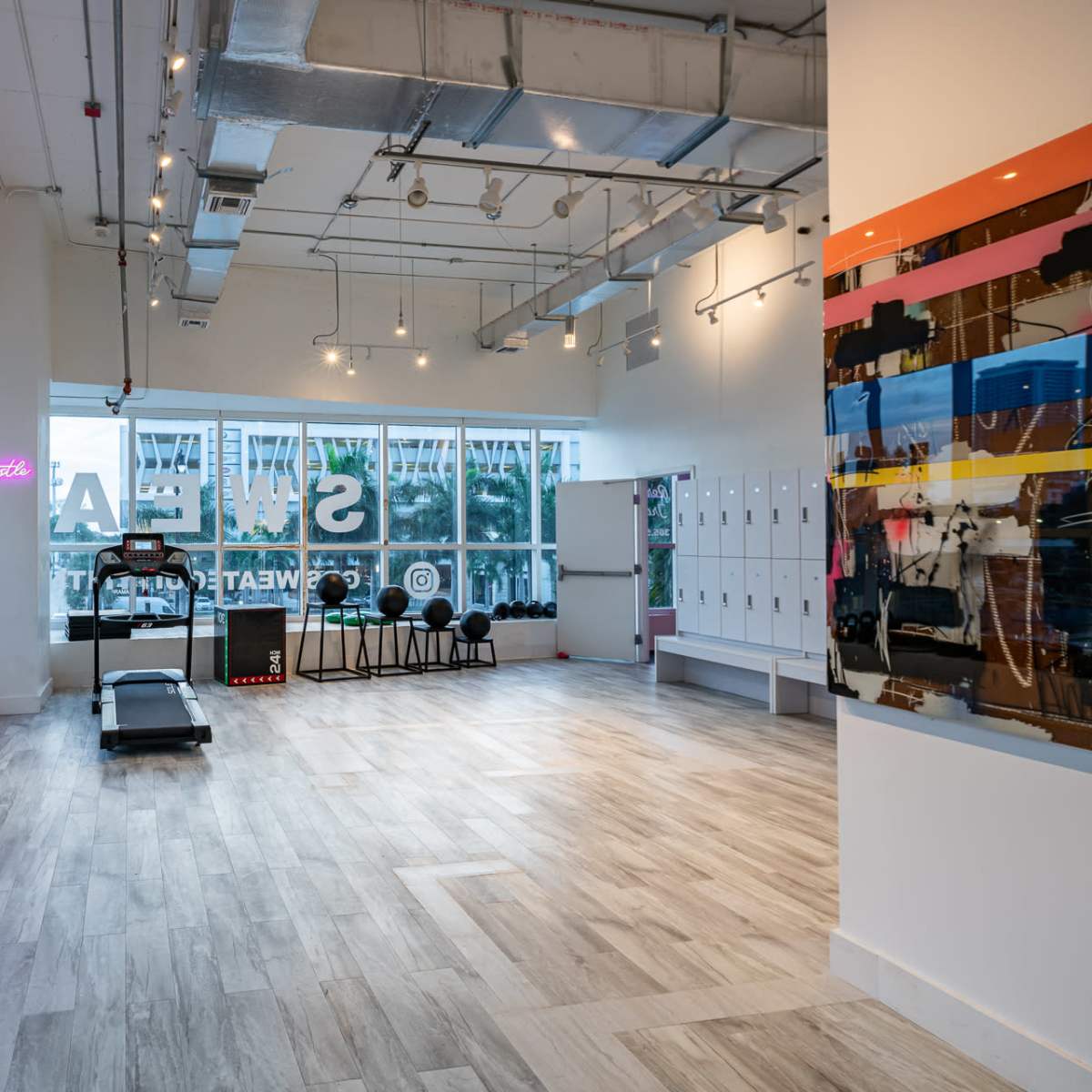 A modern gym interior with exercise equipment, large windows, and a vibrant color scheme.