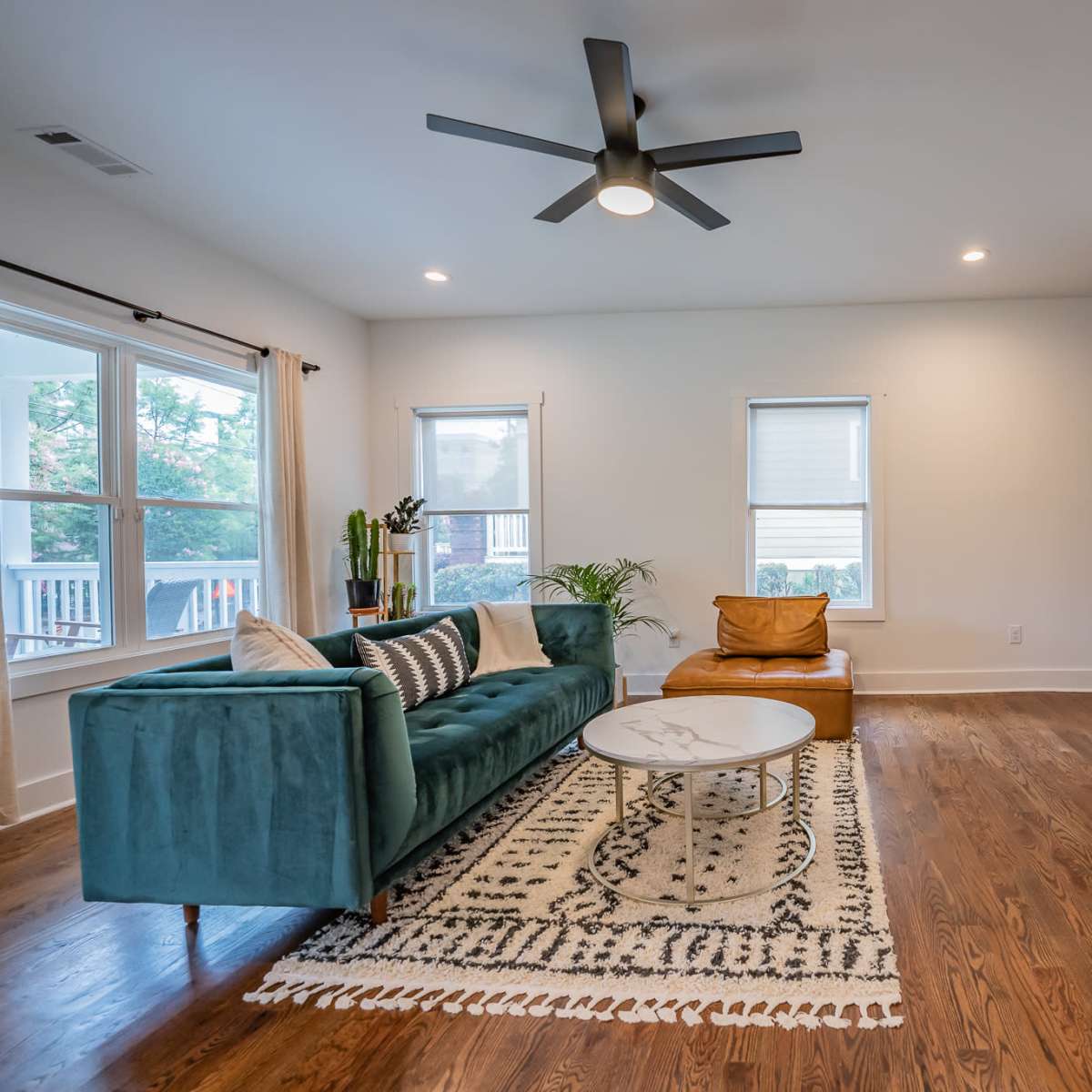 A modern living room featuring a teal sofa, a circular coffee table, and a flat-screen TV mounted on the wall.