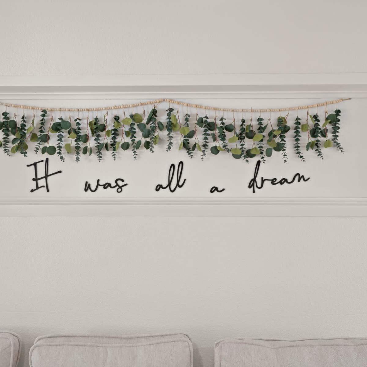 A decorative wall display features artificial greenery with the phrase "It was all a dream" beneath it.