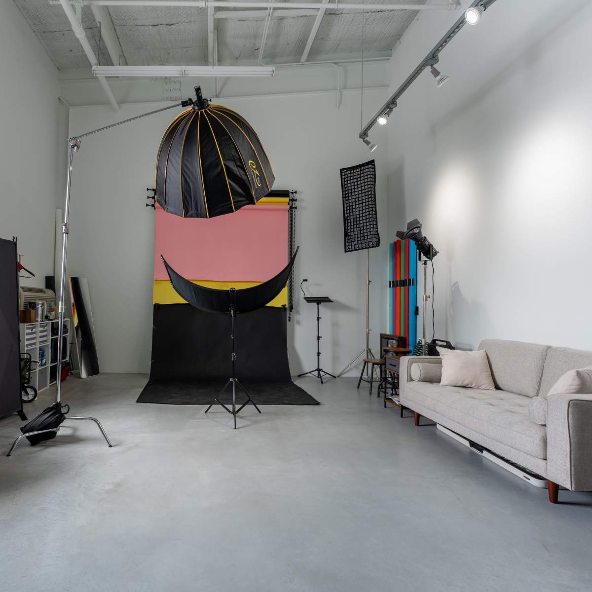 A photography studio with a large backdrop, photography equipment, and a seating area.