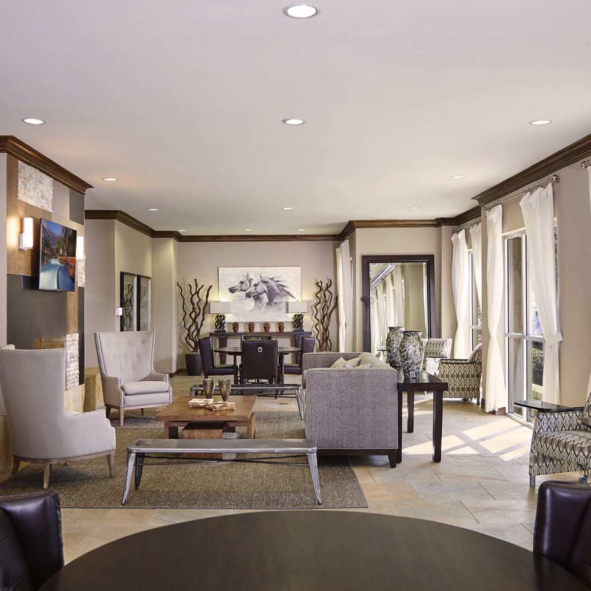 A modern lounge area with seating, a coffee table, and large windows allowing natural light.