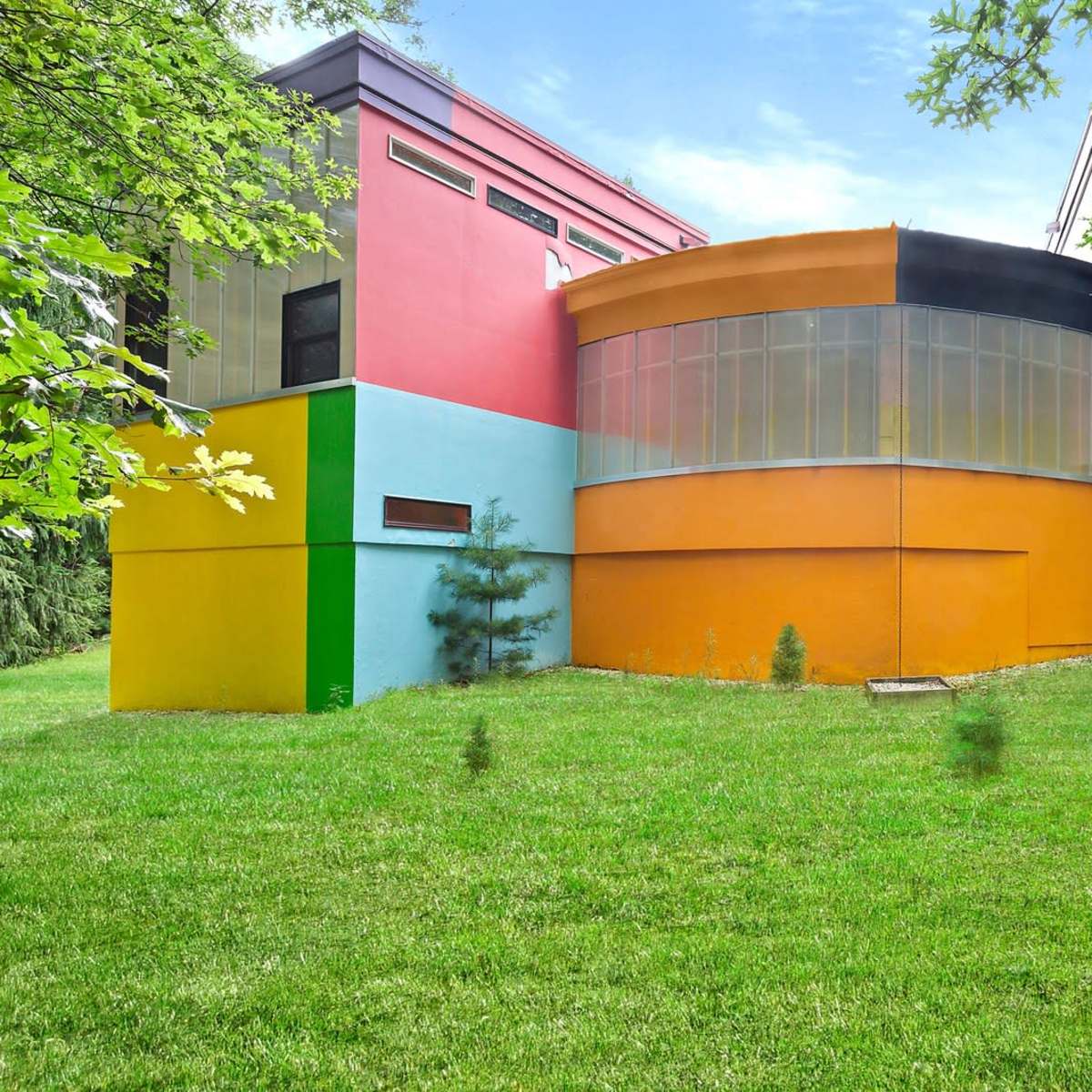 A modern architectural structure with vibrant, multicolored walls set against a grassy lawn.