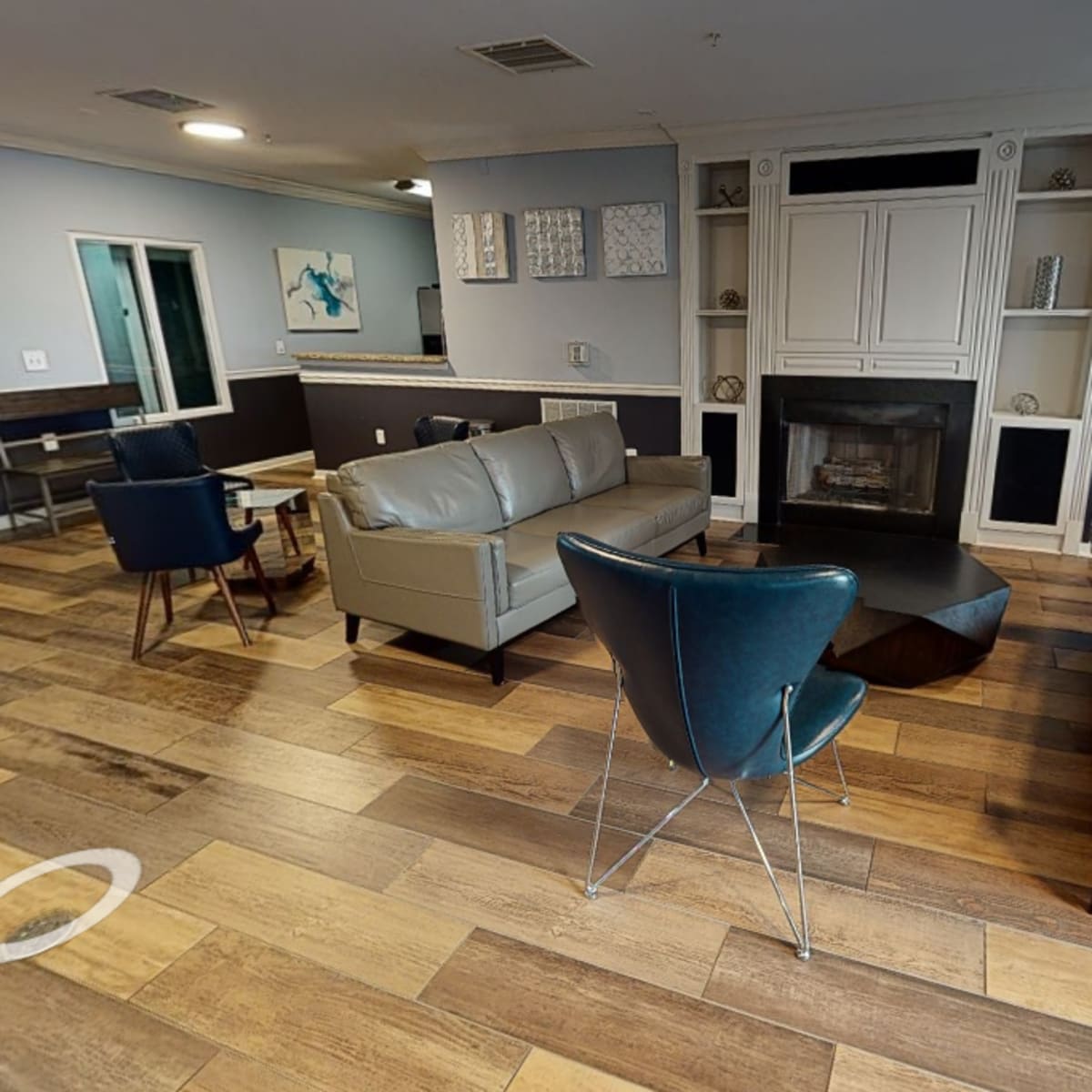 A modern living room features two sofas, a fireplace, and a dining area with a round table and chairs.