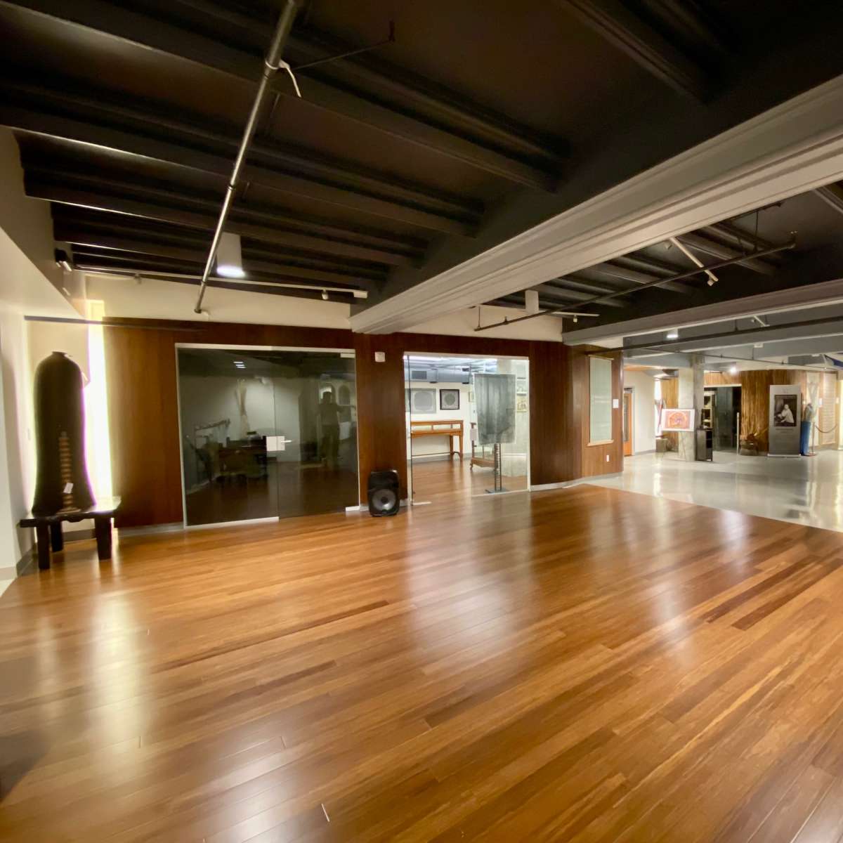 A spacious, modern interior with polished wooden floors, exposed beams, and various art pieces displayed on the walls.