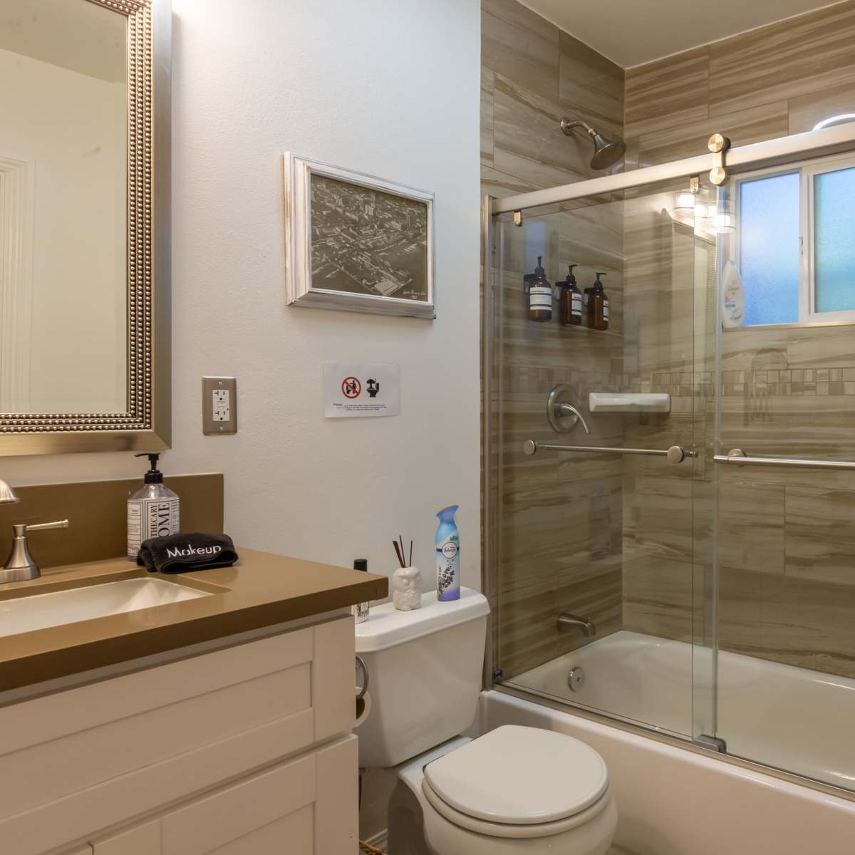A modern bathroom featuring a glass shower enclosure, a white toilet, and a sink with a mirror.