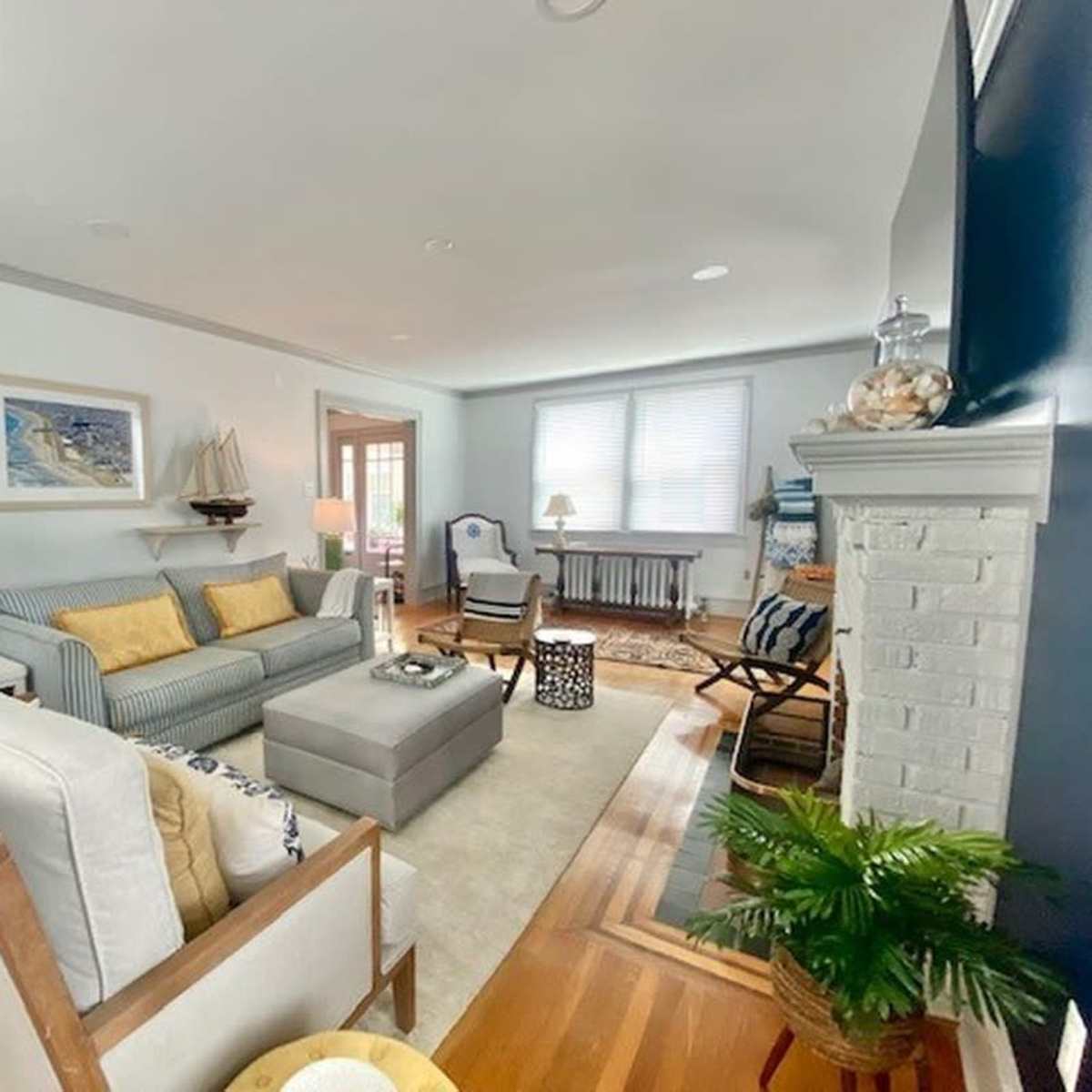 A well-lit living room with a striped sofa, a coffee table, and a fireplace, featuring a mix of furniture and decorative elements.