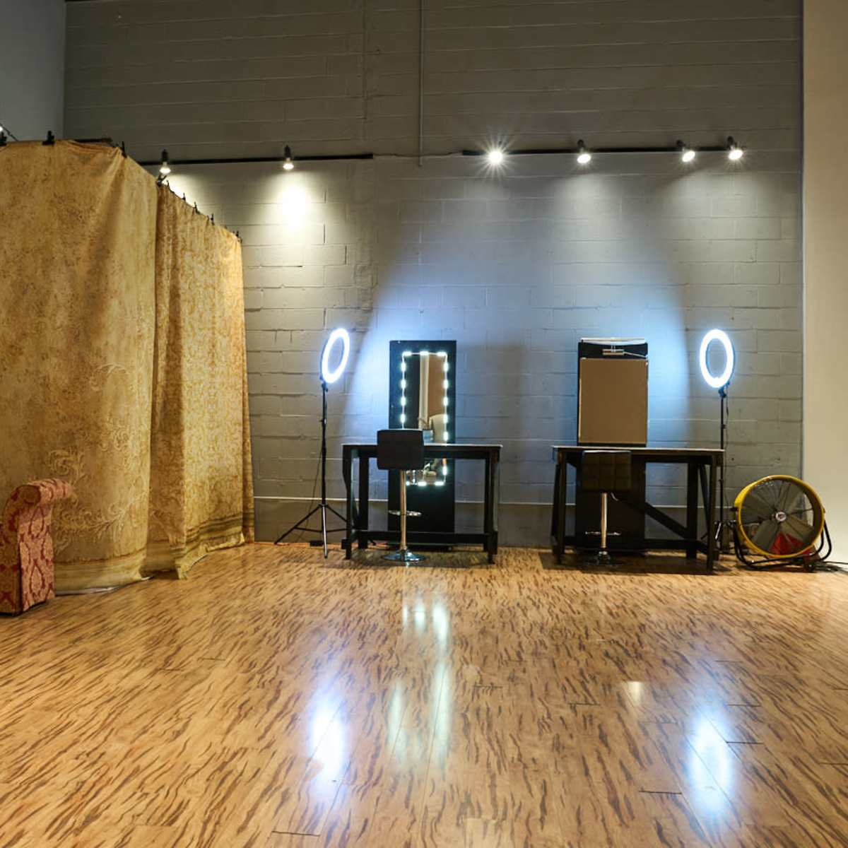 A spacious room with a patterned fabric partition, two lighted mirrors, and a table with audio equipment.