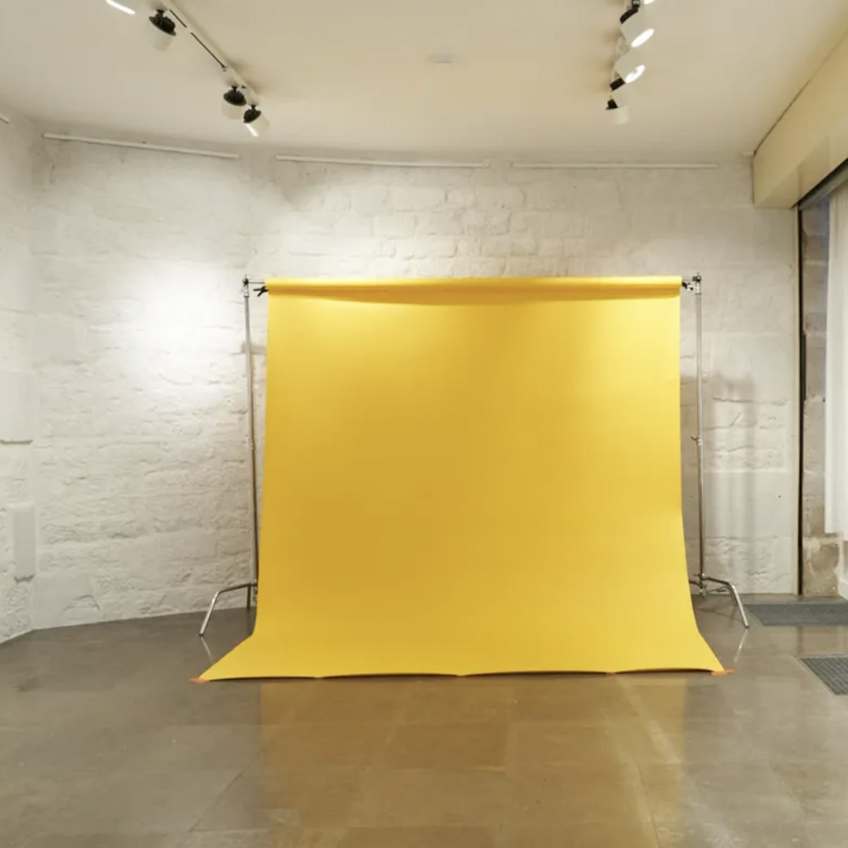 A photography studio with a yellow backdrop, a large mirror, and light-colored walls.