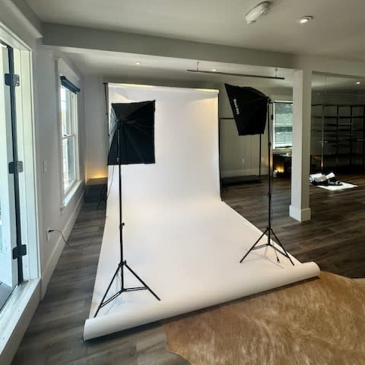 A photography studio setup with a white backdrop and two lighting stands on either side.
