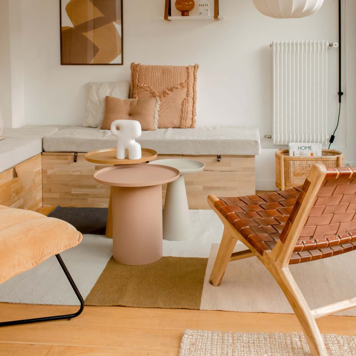 A modern living room with a cozy seating area featuring a bench, a round table, a patterned chair, and decorative elements on the walls.