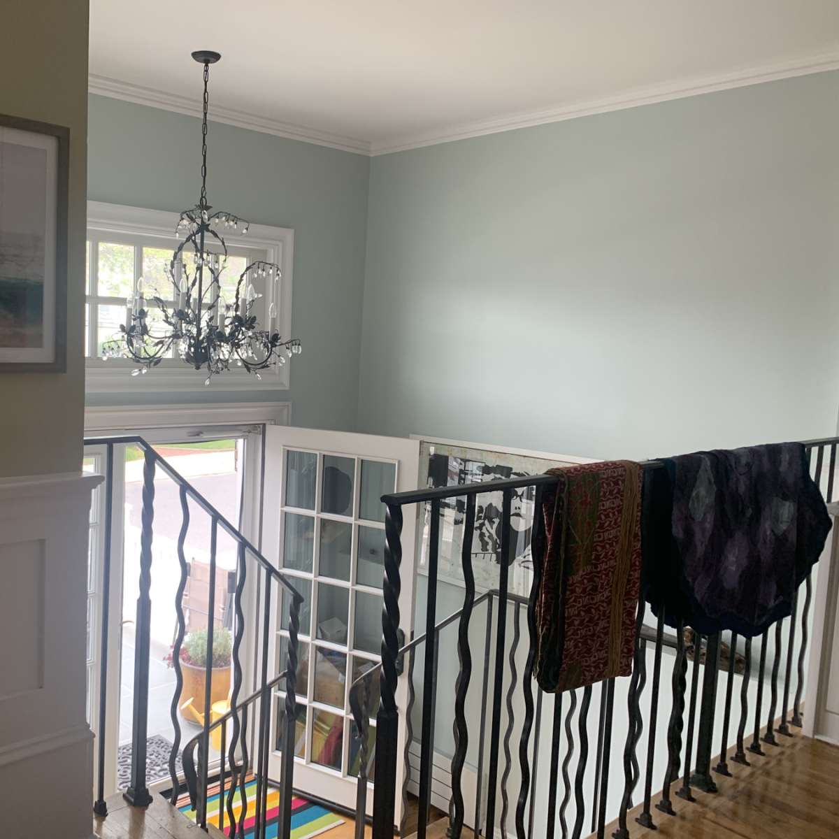 A well-lit hallway with a chandelier, a staircase, and a view of a door leading outside.