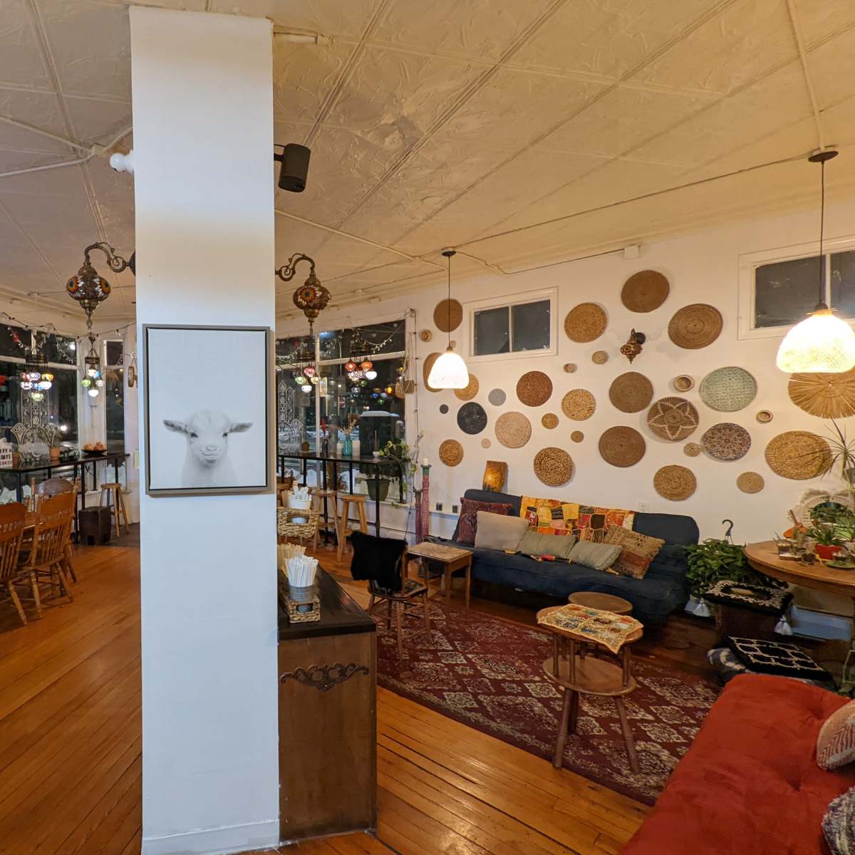 A cozy cafe interior with wooden floors, decorative wall hangings, and a mix of seating arrangements.