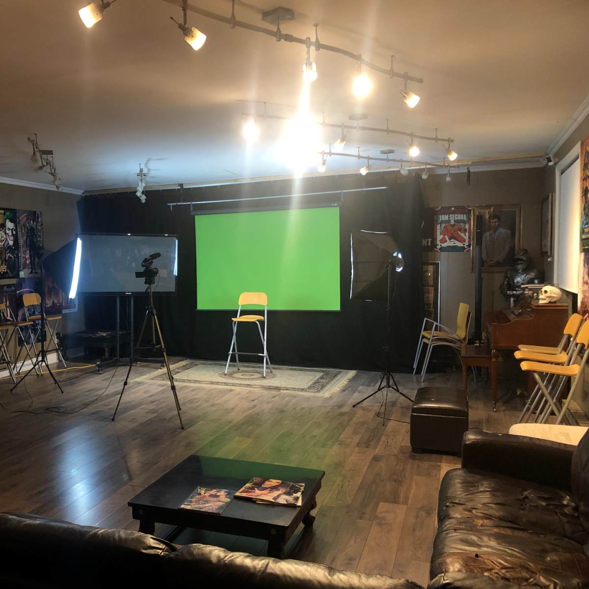 A studio setup features a green screen, lighting equipment, and seating arranged for filming.