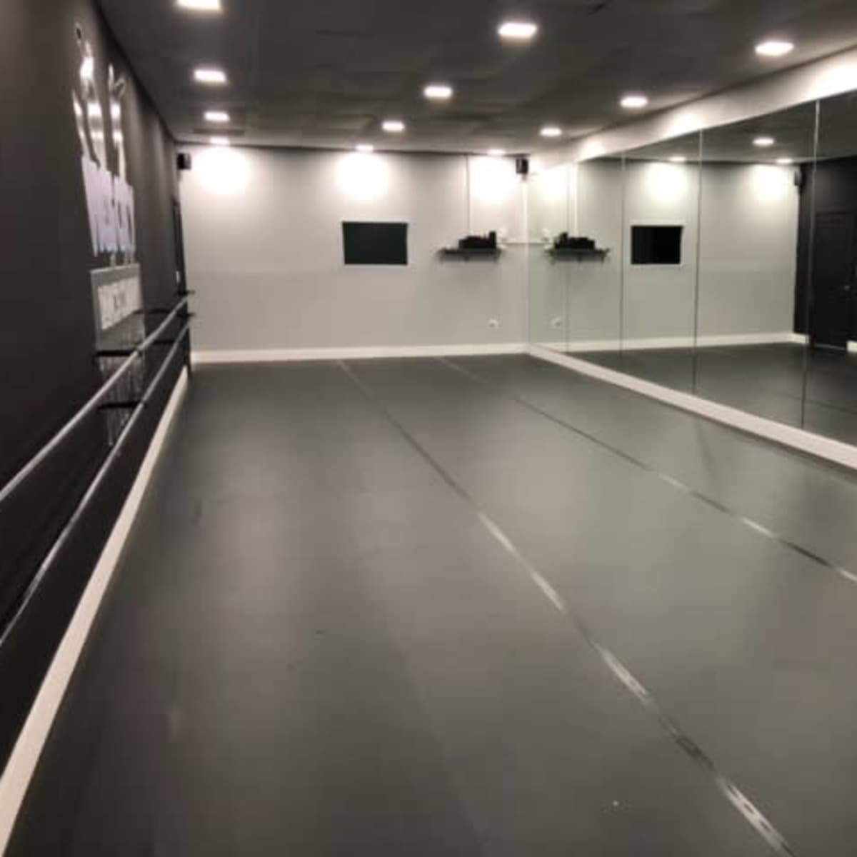 A spacious dance studio with mirrored walls and a dark floor.