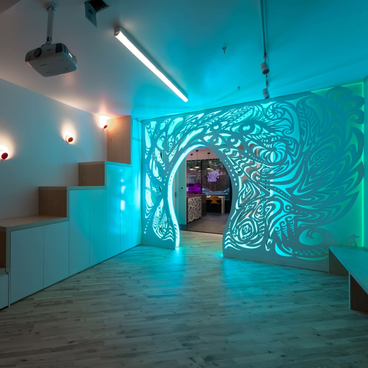 A modern, minimalist room with illuminated decorative walls and a staircase leading to an archway.