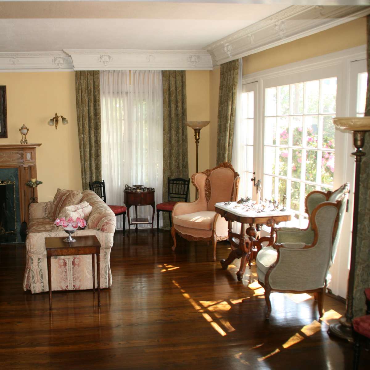 The living room features a fireplace surrounded by two sofas and a coffee table, with large windows that let in natural light.