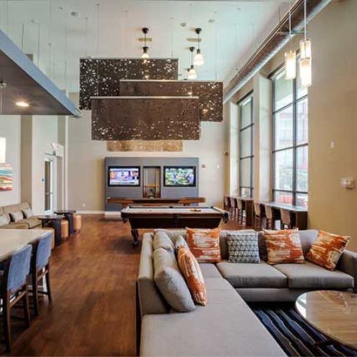 A spacious lounge area with a pool table, comfortable seating, and large windows bringing in natural light.