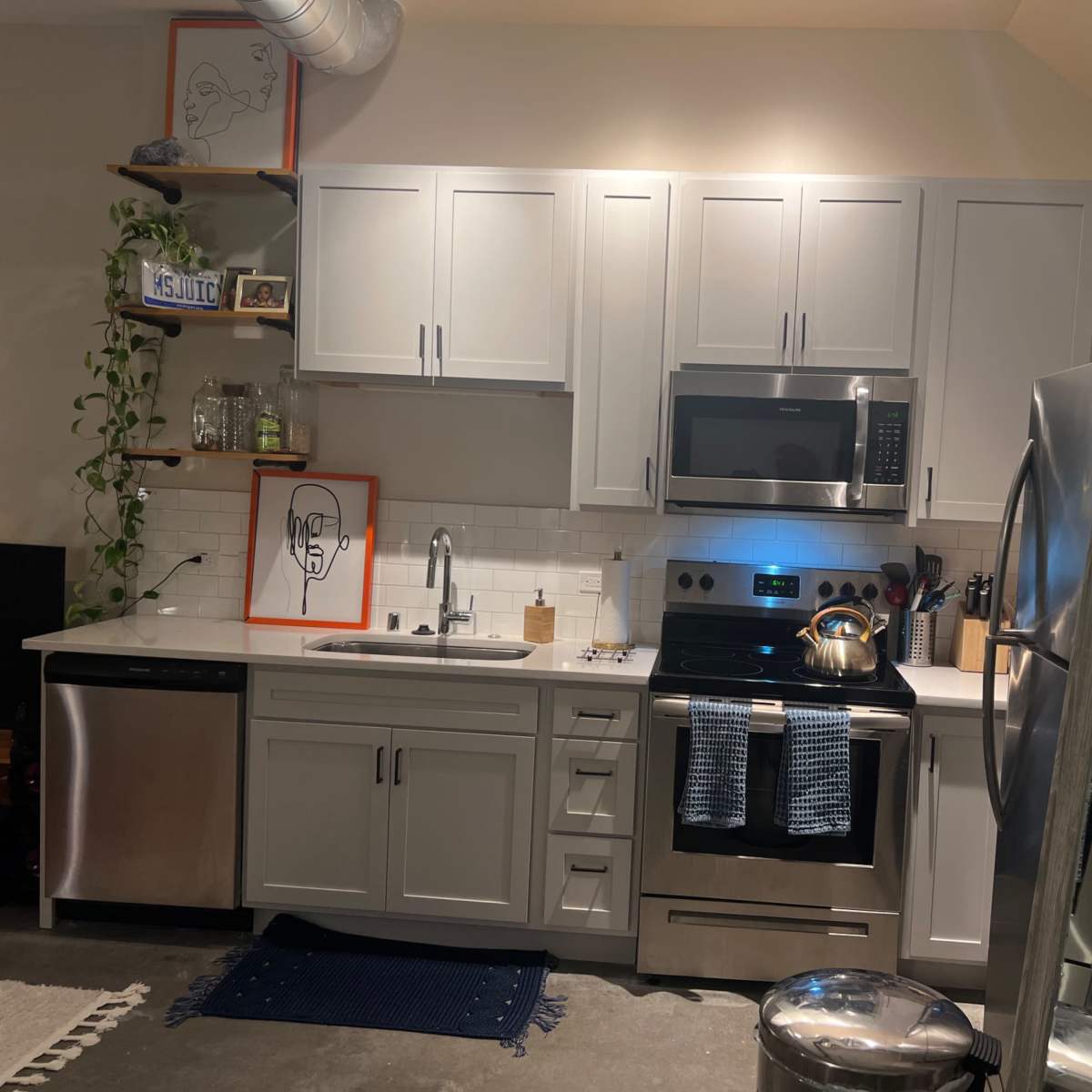 A modern kitchen with gray cabinets, stainless steel appliances, and a neatly organized countertop.