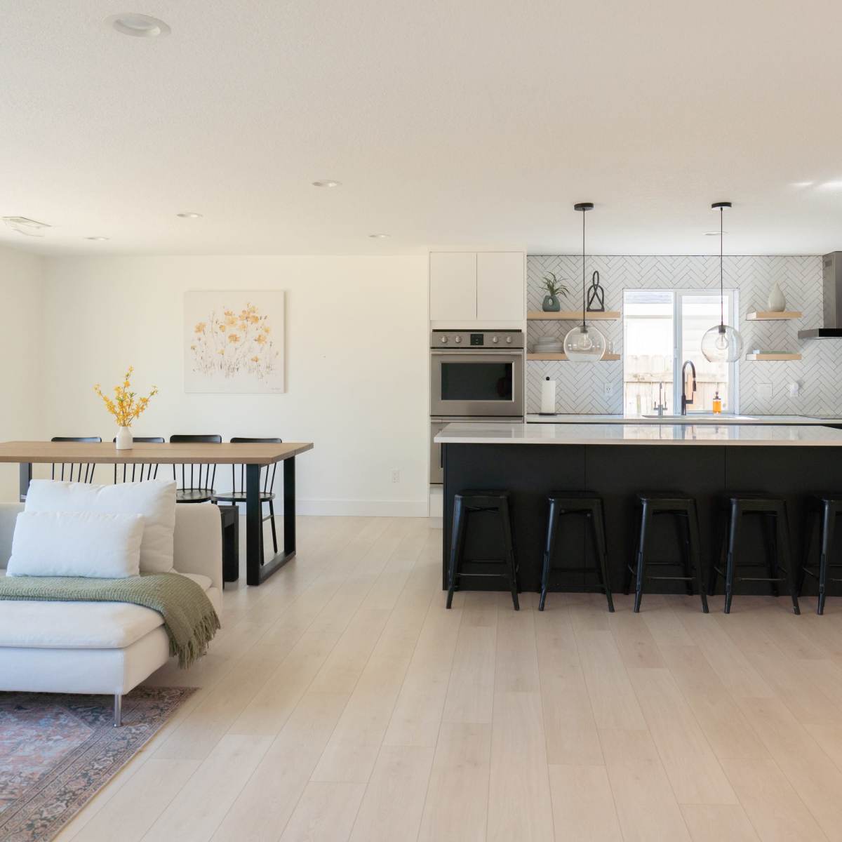 A modern kitchen and dining area featuring a large island, bar seating, a dining table, and sliding glass doors that lead to an outdoor space.