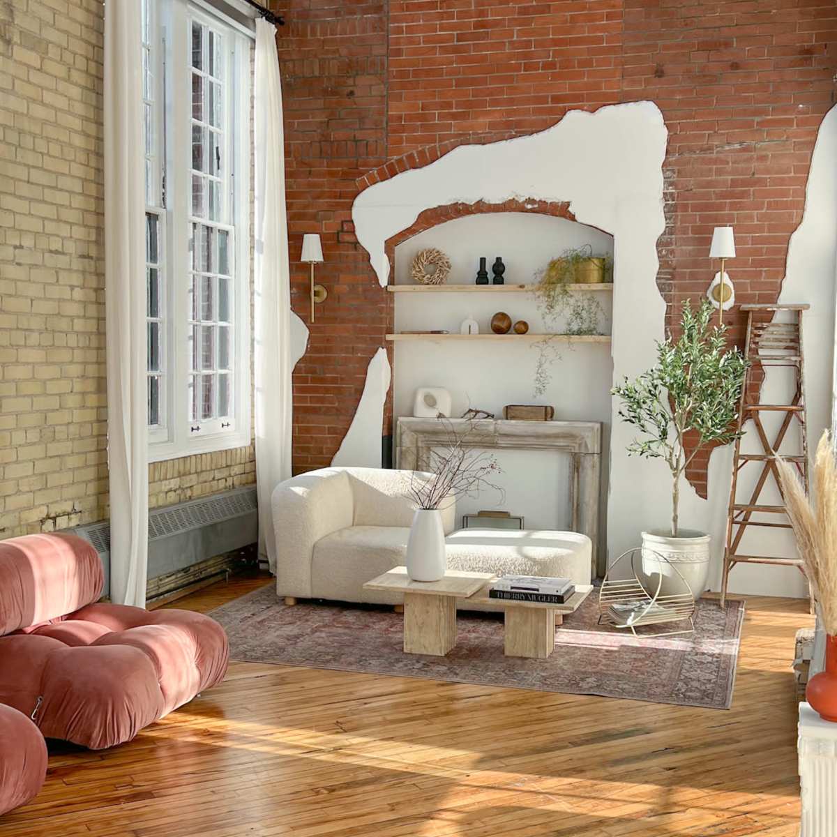 The scene shows a spacious living room featuring brick walls, large windows, a mix of modern and vintage furniture, and warm wooden floors.