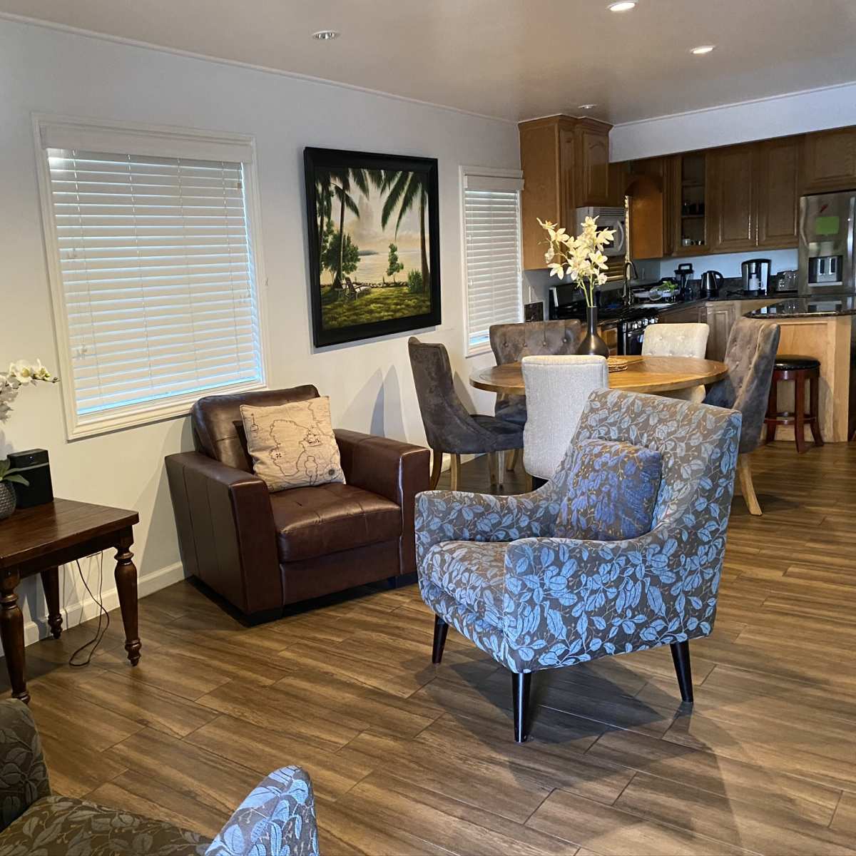 A cozy living area featuring upholstered chairs, a wooden table, and framed artwork on the walls.