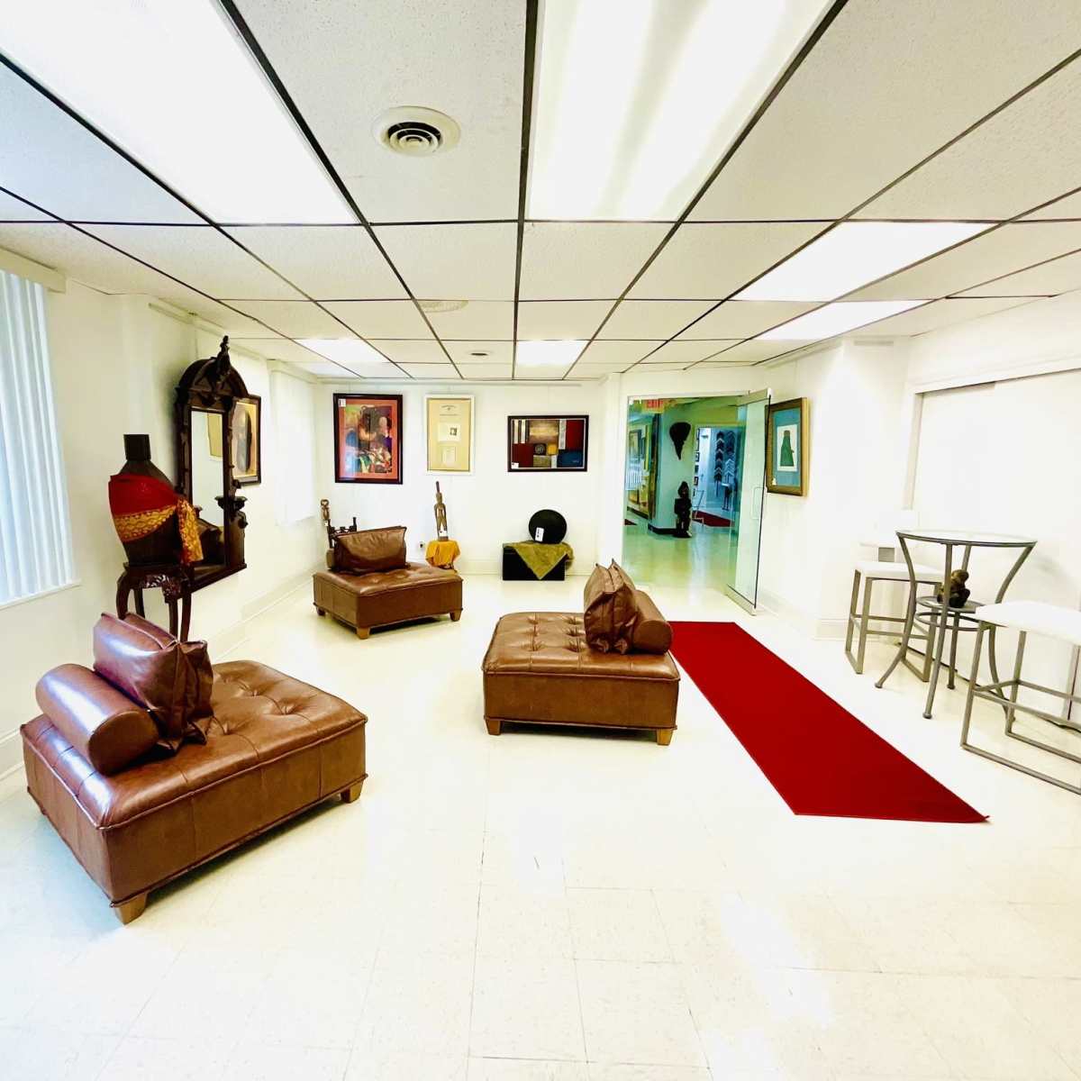 A spacious room with two brown leather sofas, a red area rug, and a small dining table with white chairs.