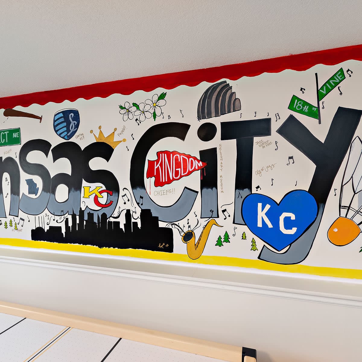 A colorful mural on a wall that displays various artistic representations and text related to Kansas City.