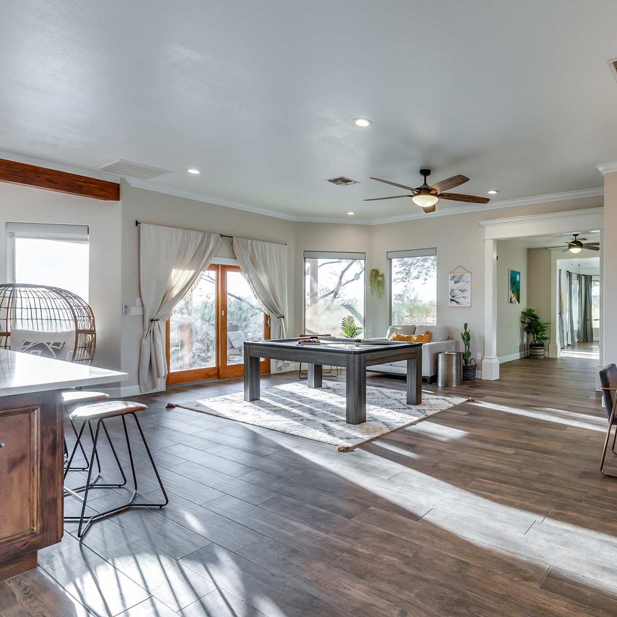 A spacious dining and living area features a pool table, dining table, and large windows with natural light.