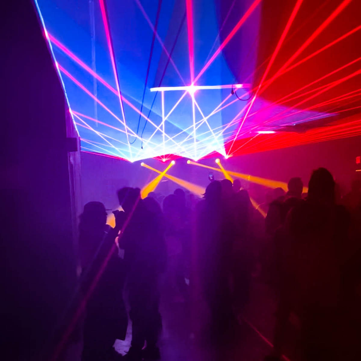 A crowded nightclub scene features colorful laser lights cutting through the darkness.