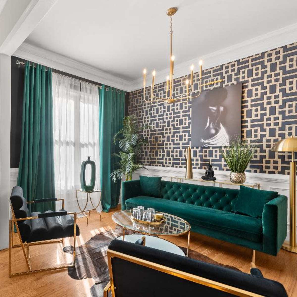 A stylish living room with green curtains, a green velvet sofa, and a modern coffee table beside a staircase and an entrance door.