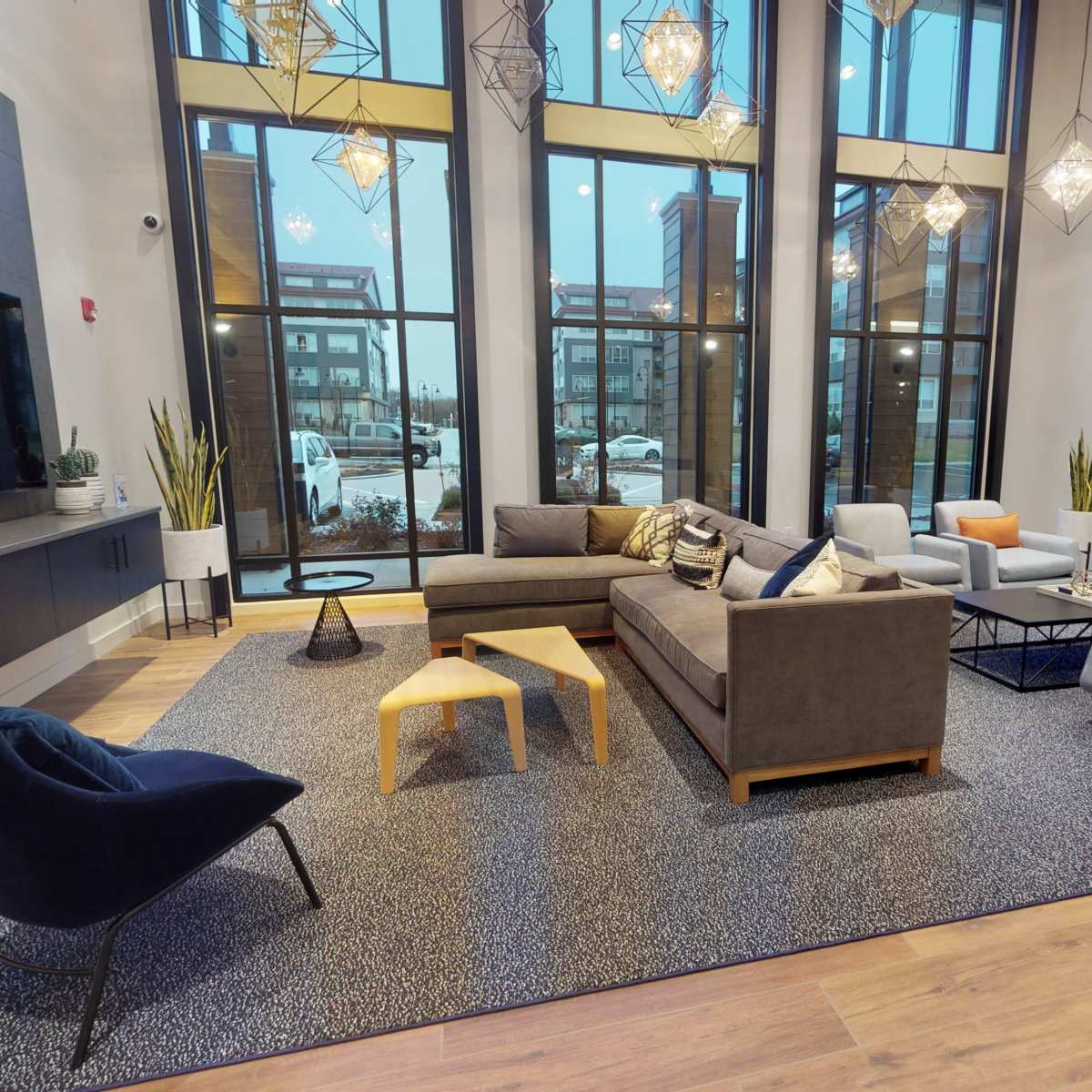 A modern lounge area with large windows, contemporary furniture, and decorative lighting.